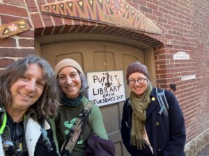 Artists standing in front of The Puppet Free Library Open 2 to 7.