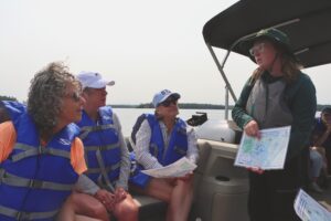 Captain Sal showing conserved land on a map to floating classroom participants