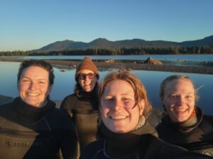 Four dive team members smile in front of Flagstaff Lake and the Bigelows